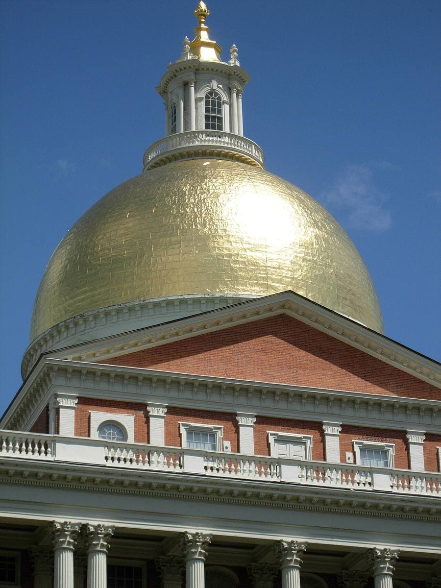 A gold dome and lantern above a red-brick pediment against blue sky