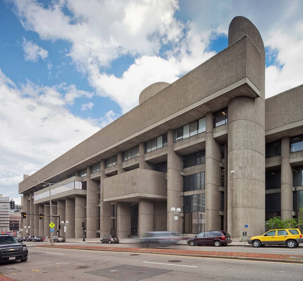 A ribbed concrete building with deep overhangs on a street corner