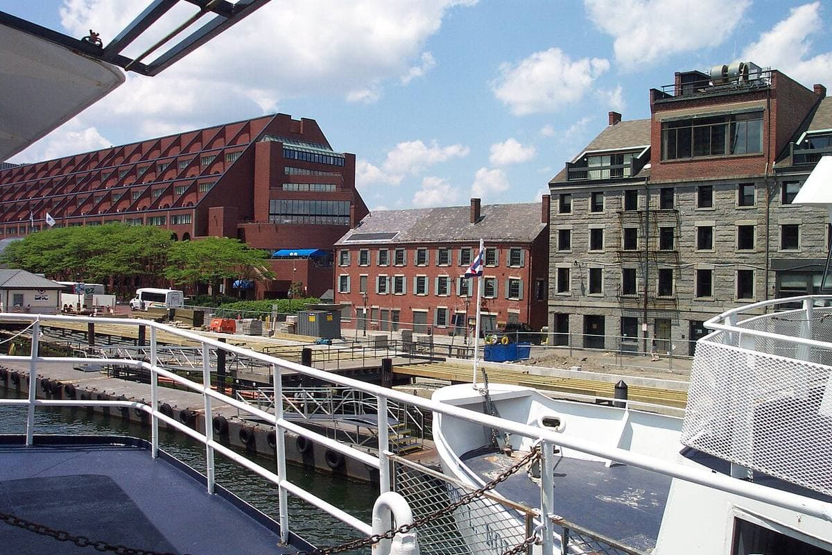 Brick and granite buildings on a wharf seen from the deck of a boat