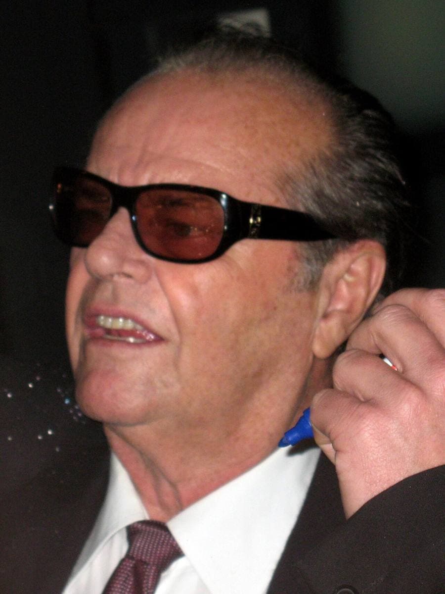 Jack Nicholson in dark glasses, smiling, a hand raised to his ear