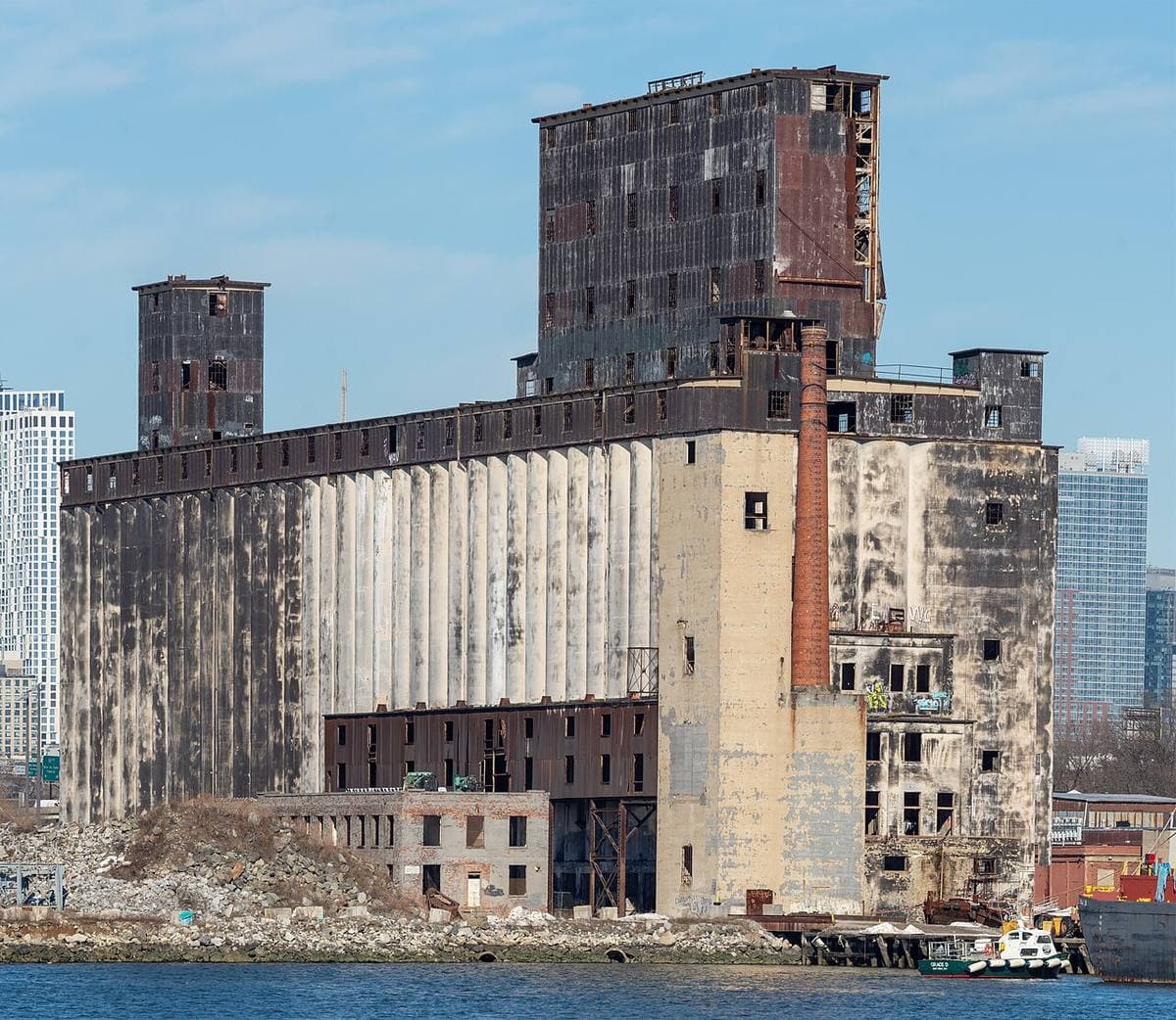 A weathered concrete grain elevator rising beside the water