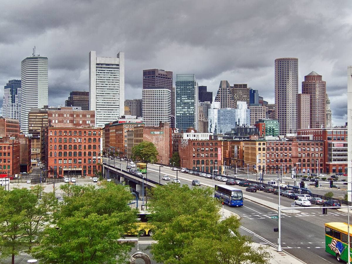 Downtown towers over brick warehouses and a busy road on a grey day