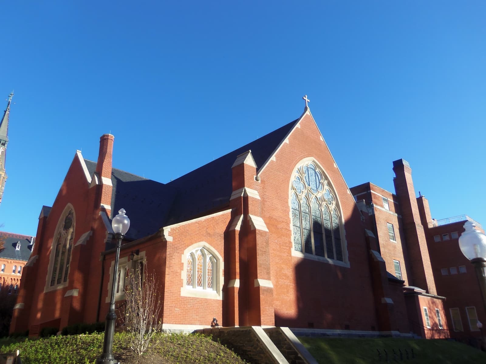 A red-brick Gothic chapel with a large pointed window under a blue sky