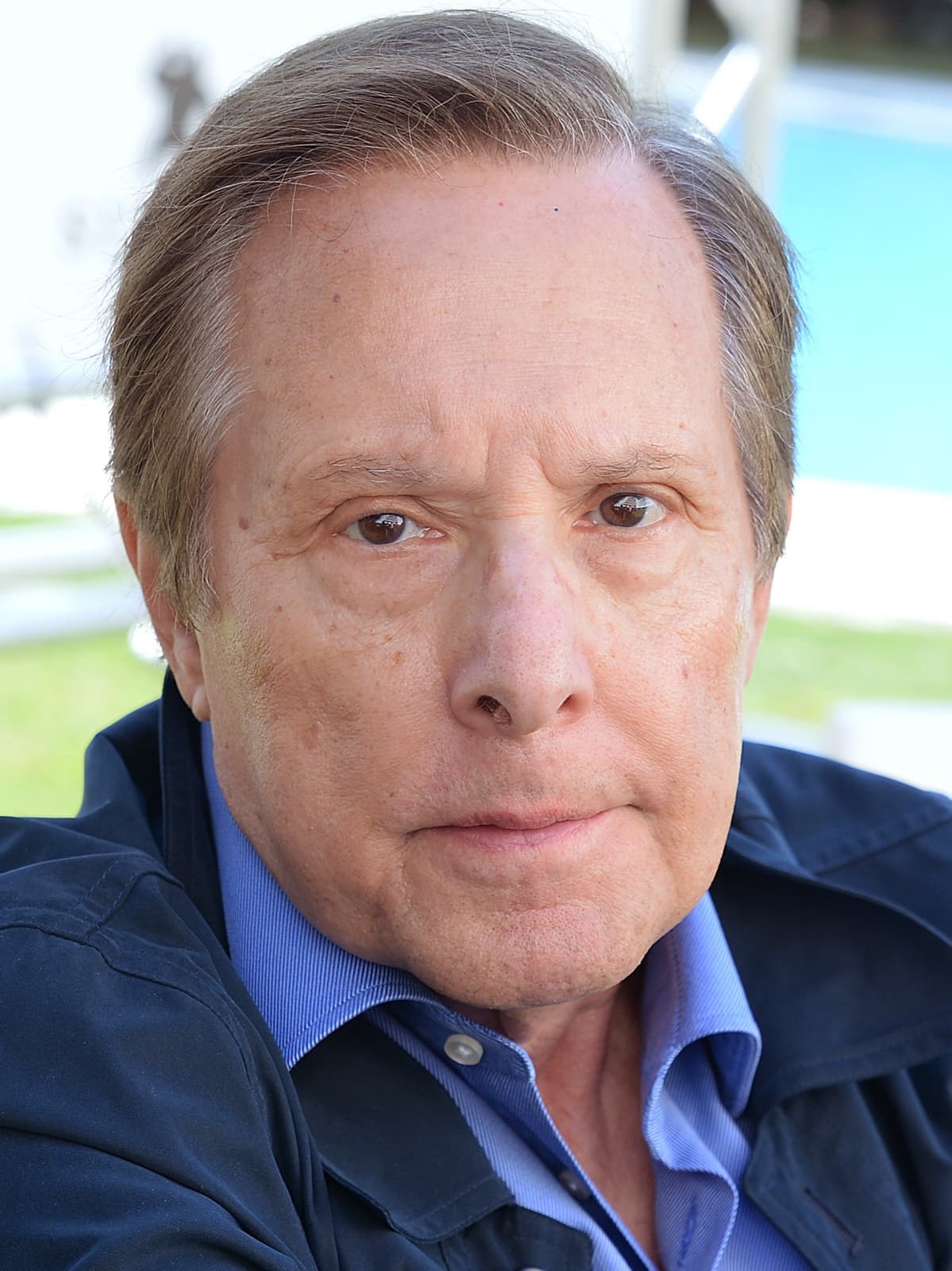 William Friedkin, grey hair, navy jacket over a blue shirt, looking at the camera