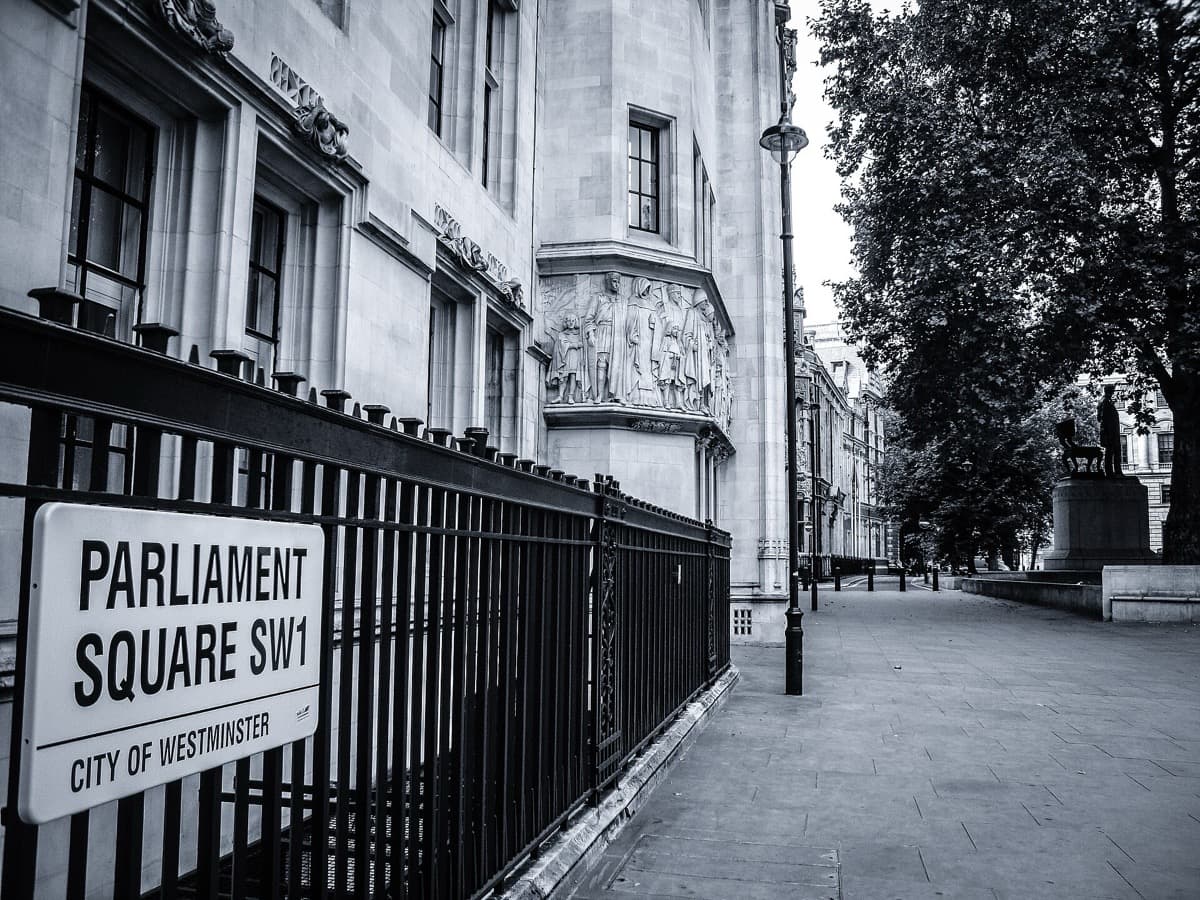 A green square with statues and trees beside the Houses of Parliament
