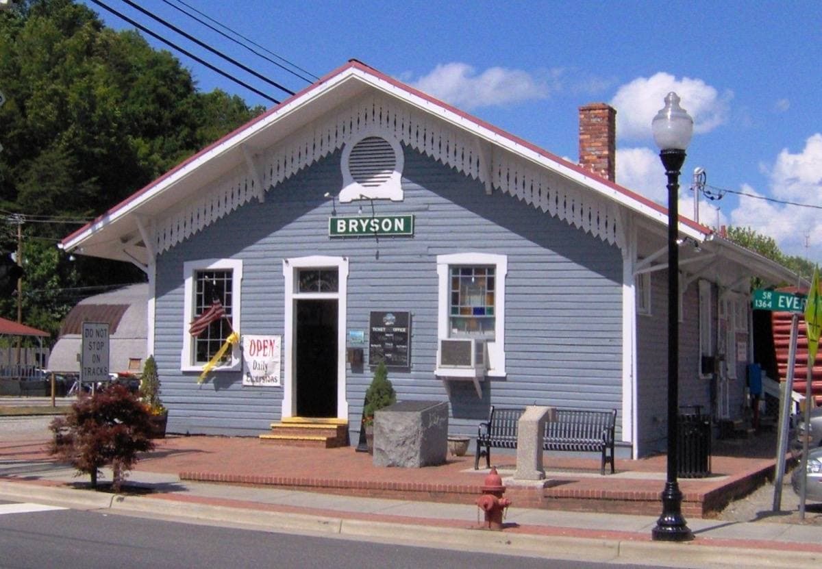 A railway depot building with a train beside it in Bryson City