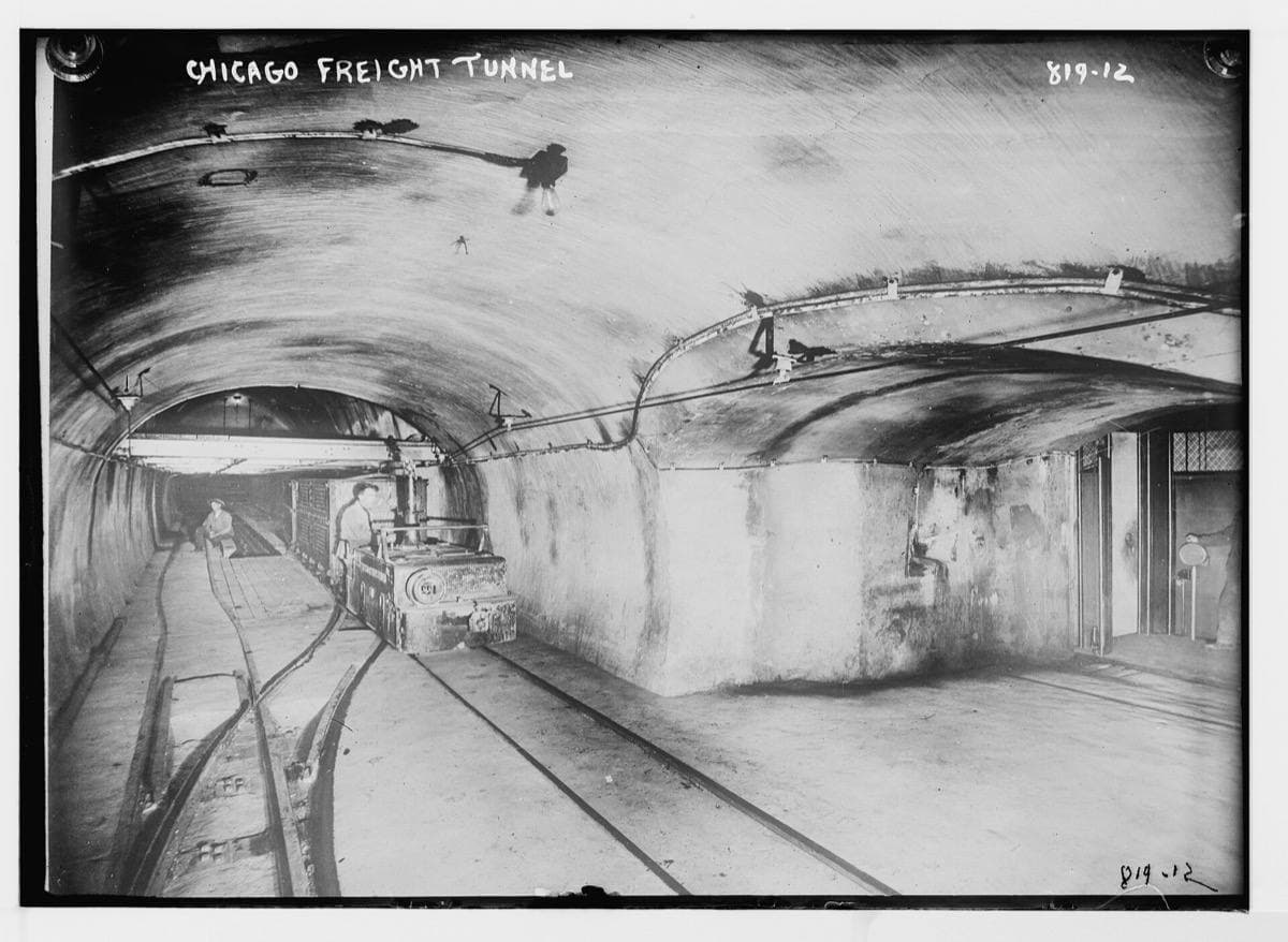 Narrow-gauge freight cars on tracks in a brick tunnel