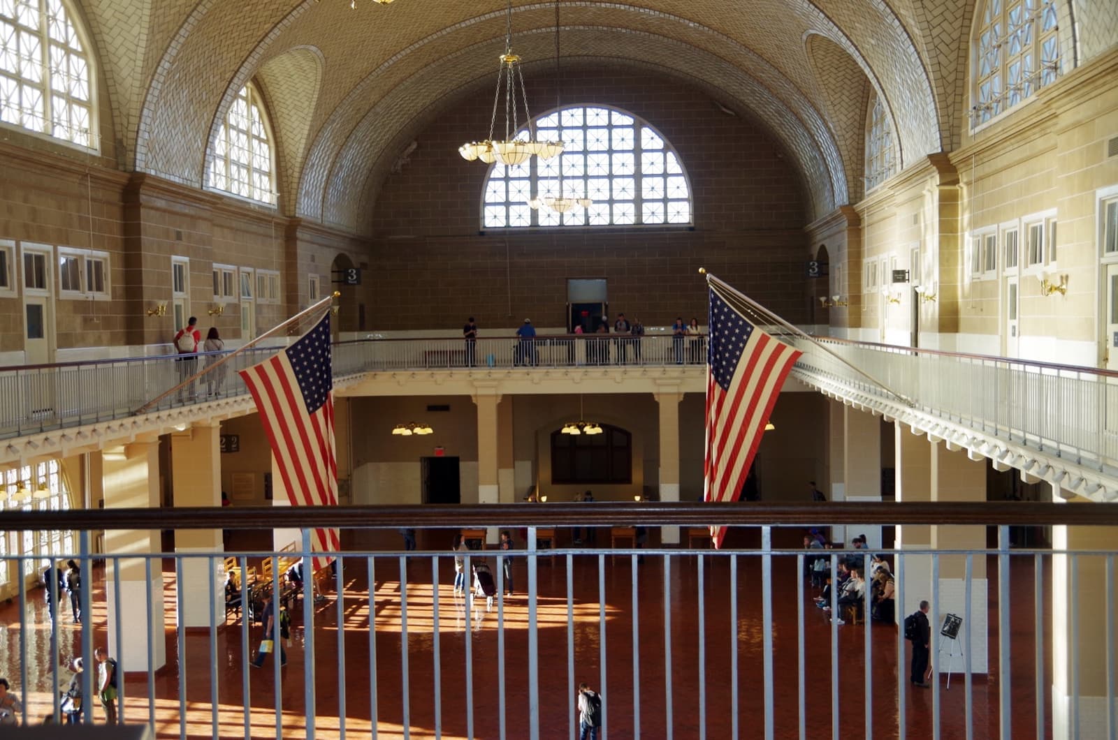 A vaulted hall with arched windows, a gallery and American flags