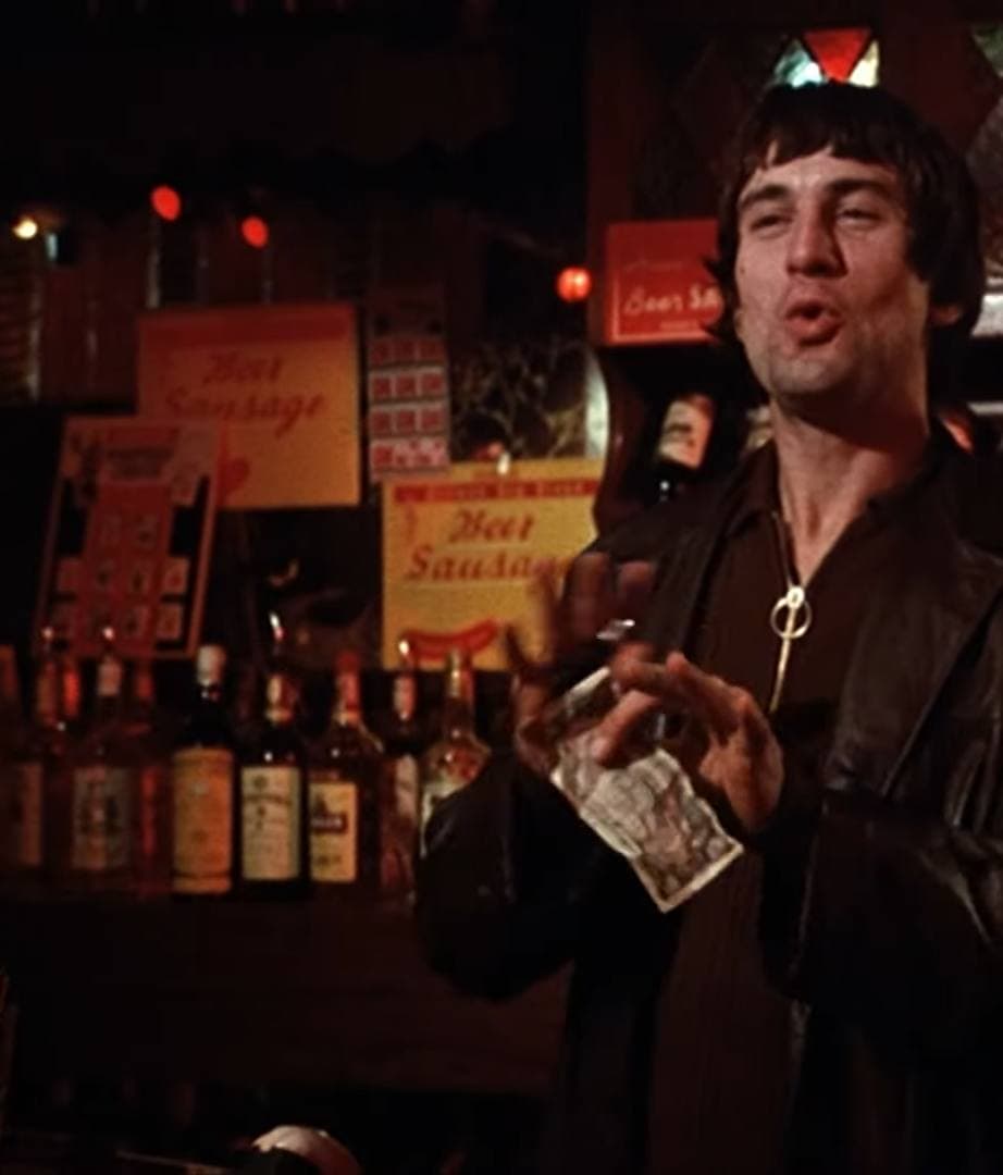 Robert De Niro in a leather jacket in a red-lit bar
