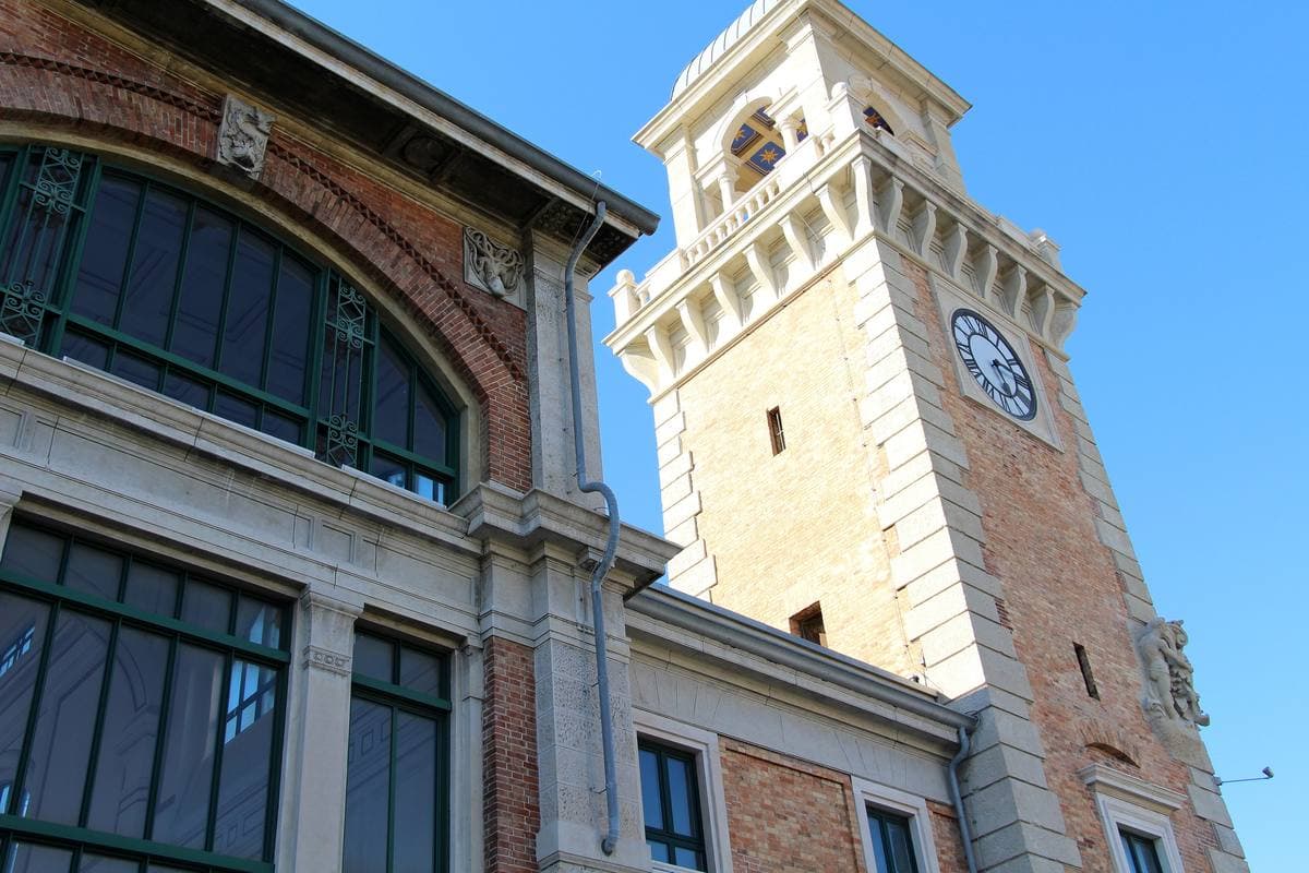 The arched windows of the old fish market hall and its clock tower against a blue sky