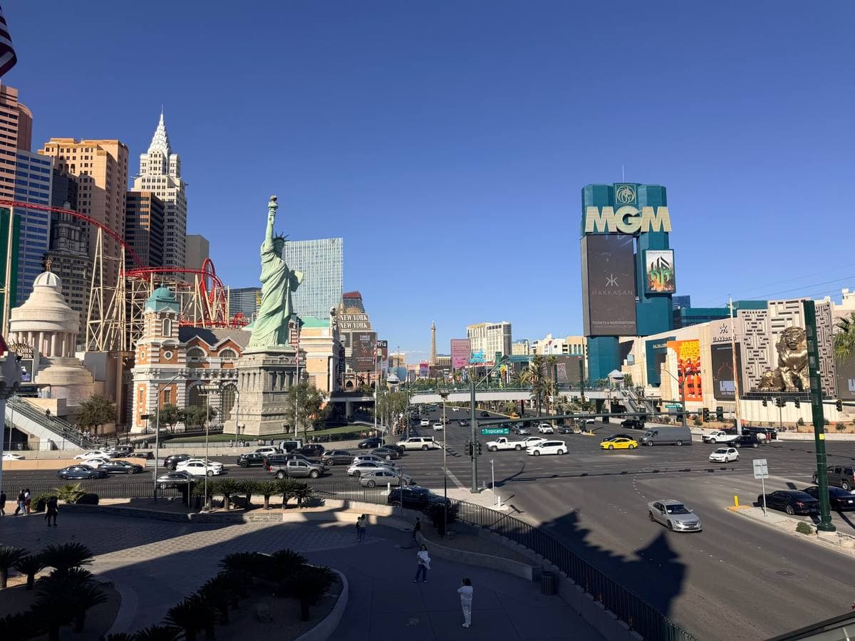 A wide Las Vegas intersection with traffic lights and hotels beyond