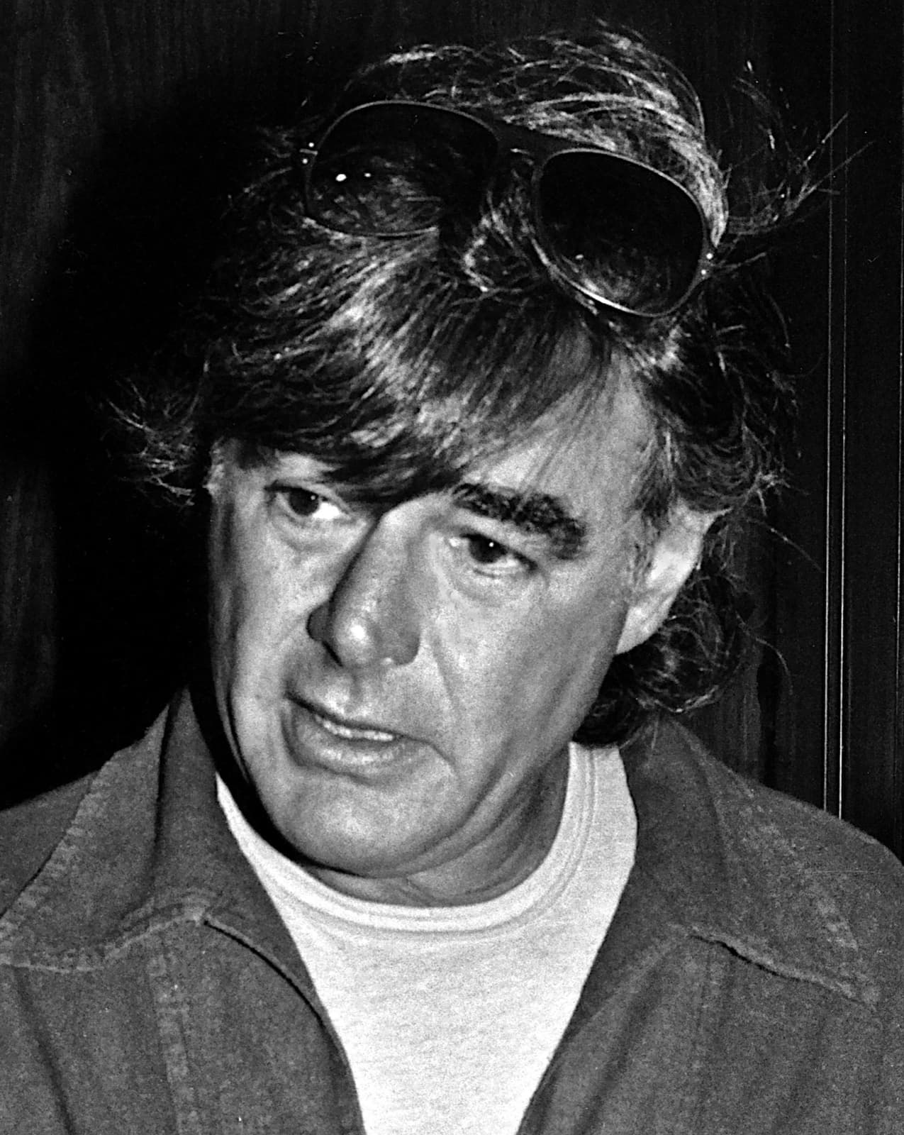 Richard Donner in black and white, sunglasses pushed up into thick hair, talking