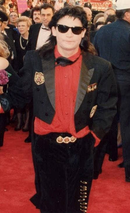 Corey Feldman in 1989 in sunglasses, a red shirt and a black jacket on the red carpet