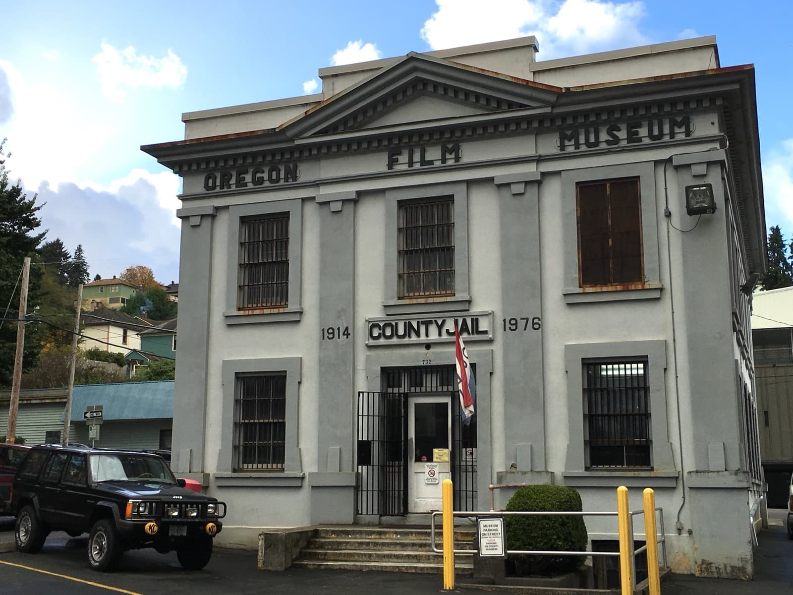 A pale two-storey neoclassical building lettered Oregon Film Museum and County Jail, a black jeep parked out front