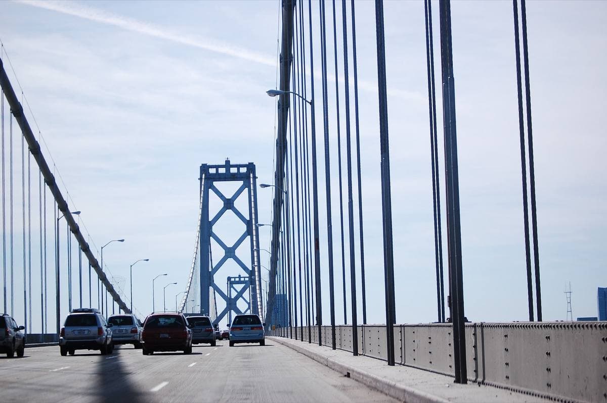 Cars on the upper deck of a suspension bridge with the towers and cables ahead