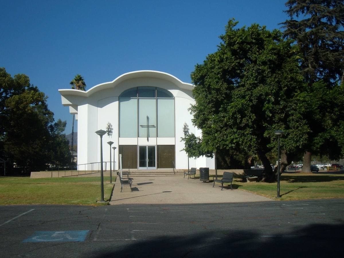 A modernist church with a tall peaked roof and a wall of glass