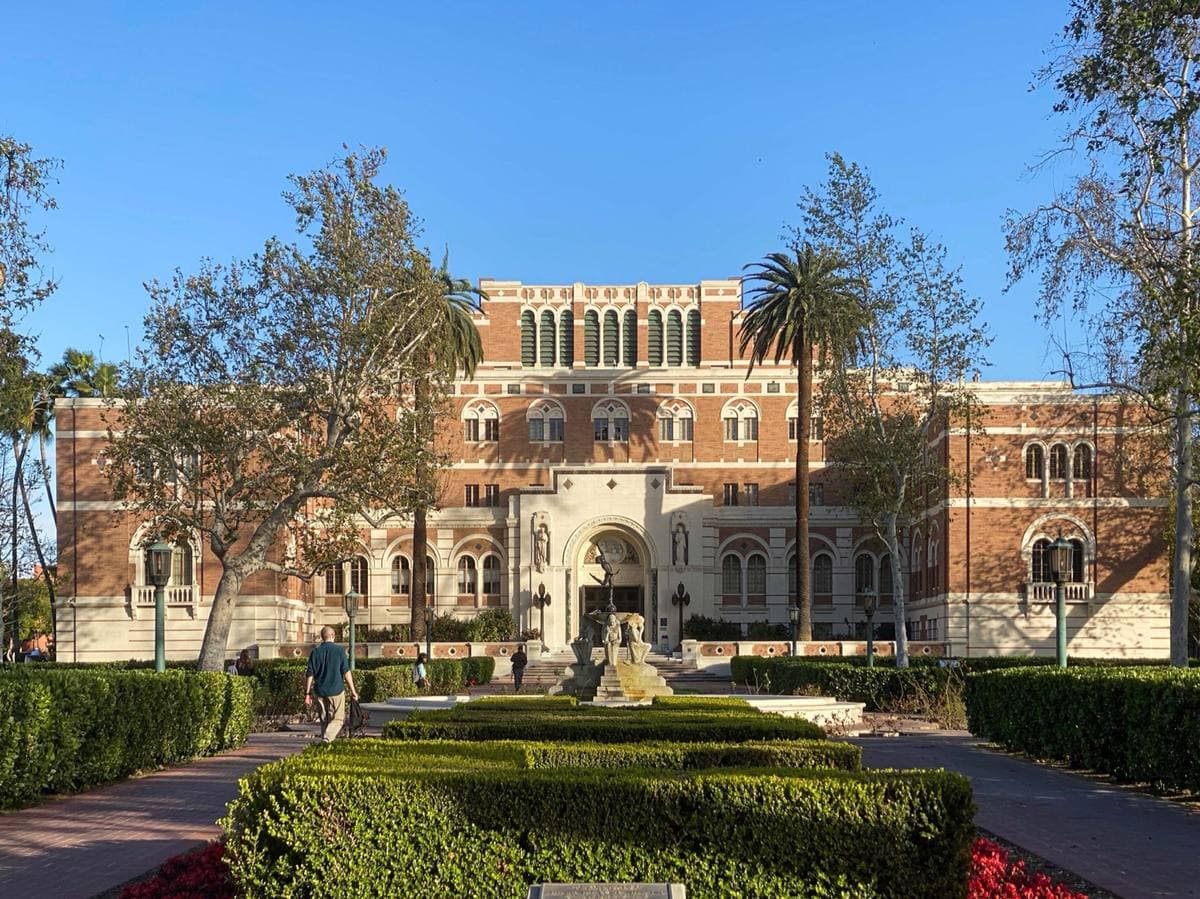A brick Romanesque library with an arched entrance and a tower, under blue sky