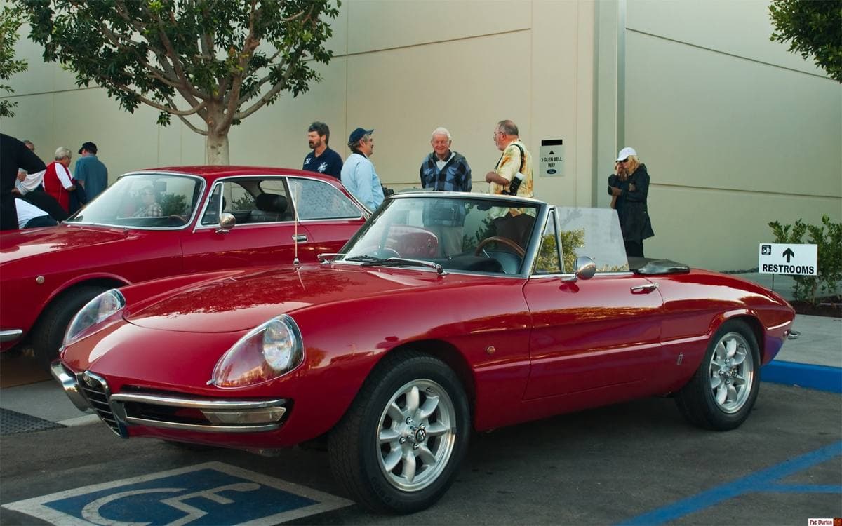 A small red open-top Italian roadster with round covered headlamps