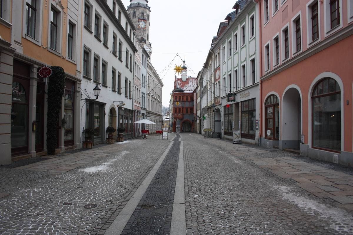 A narrow street of pastel Renaissance houses leading to the town hall tower