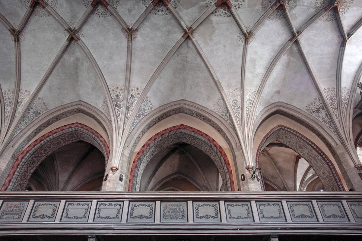 A Gothic nave with a carved altar and ribbed vaults