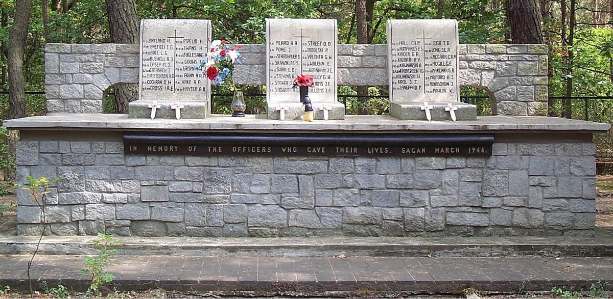 A stone memorial with a plaque among trees beside a road