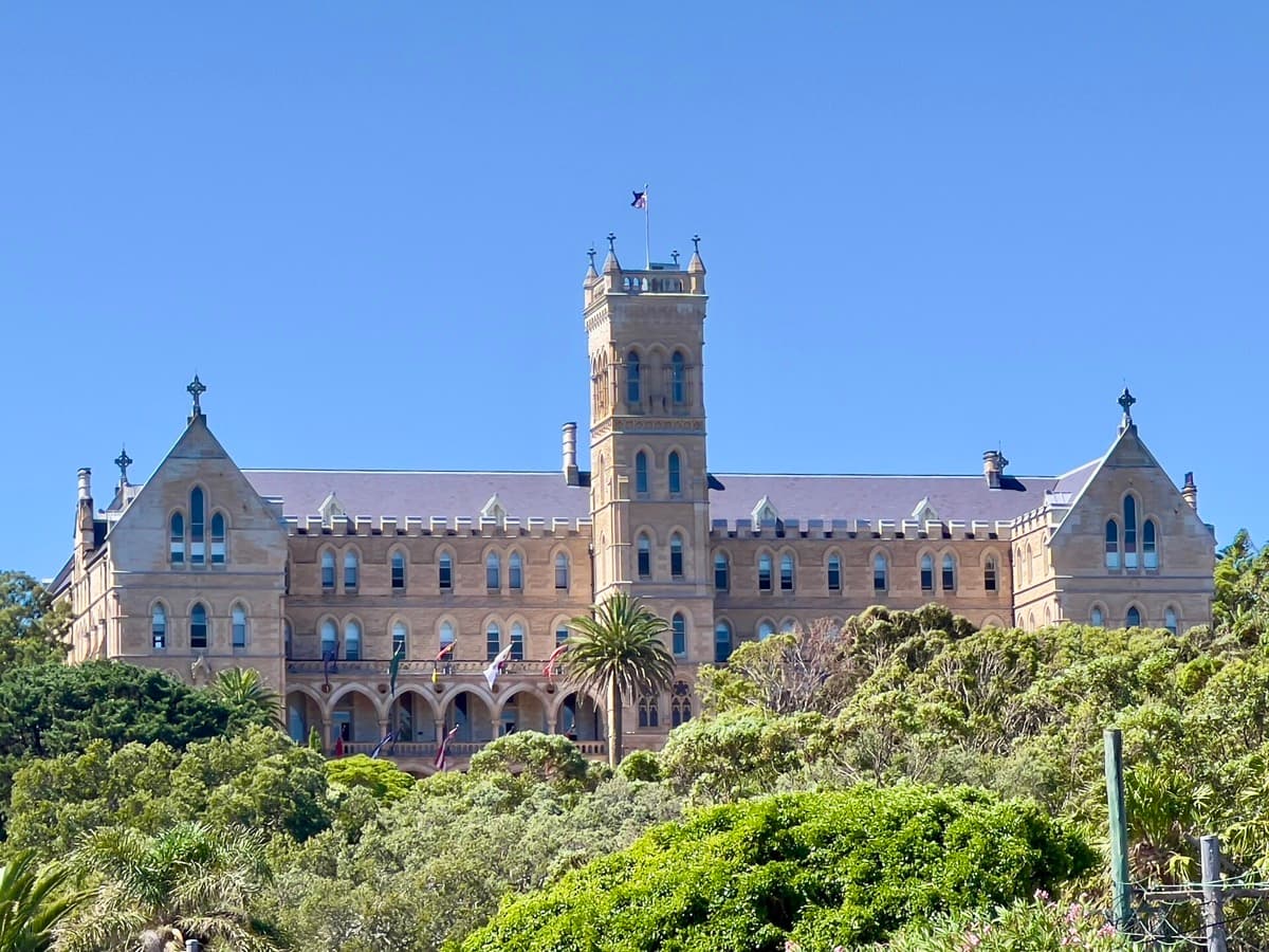 A large sandstone seminary building on a hill under a pale sky