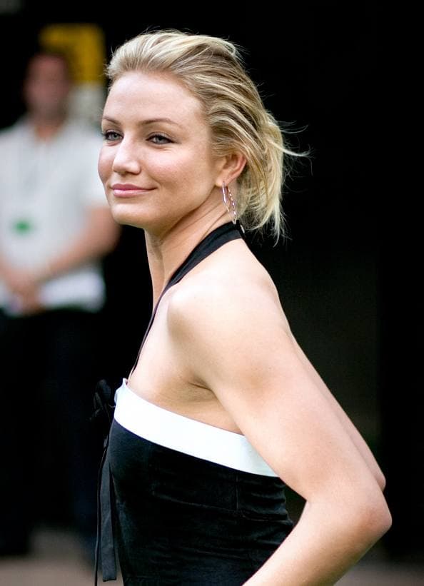 Cameron Diaz, blonde hair pushed back, looking over her shoulder in a black halter-neck dress