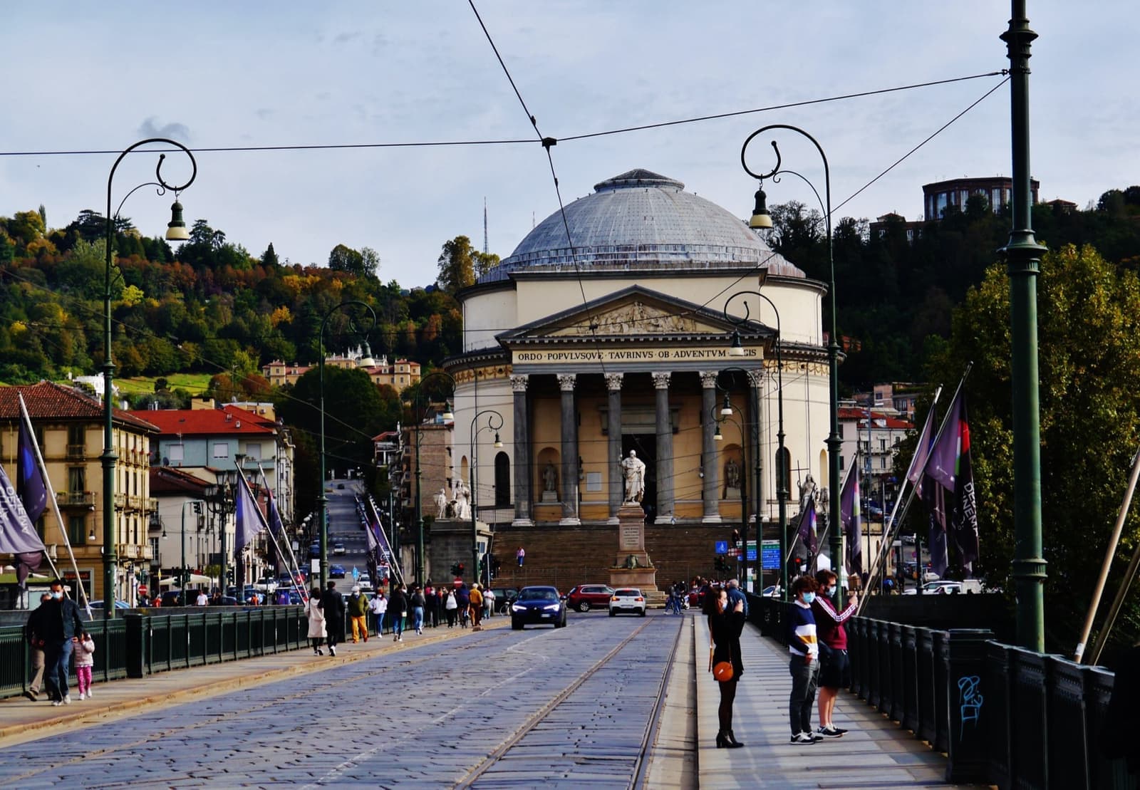 A domed neoclassical church with a columned portico above a broad flight of steps, seen across a bridge