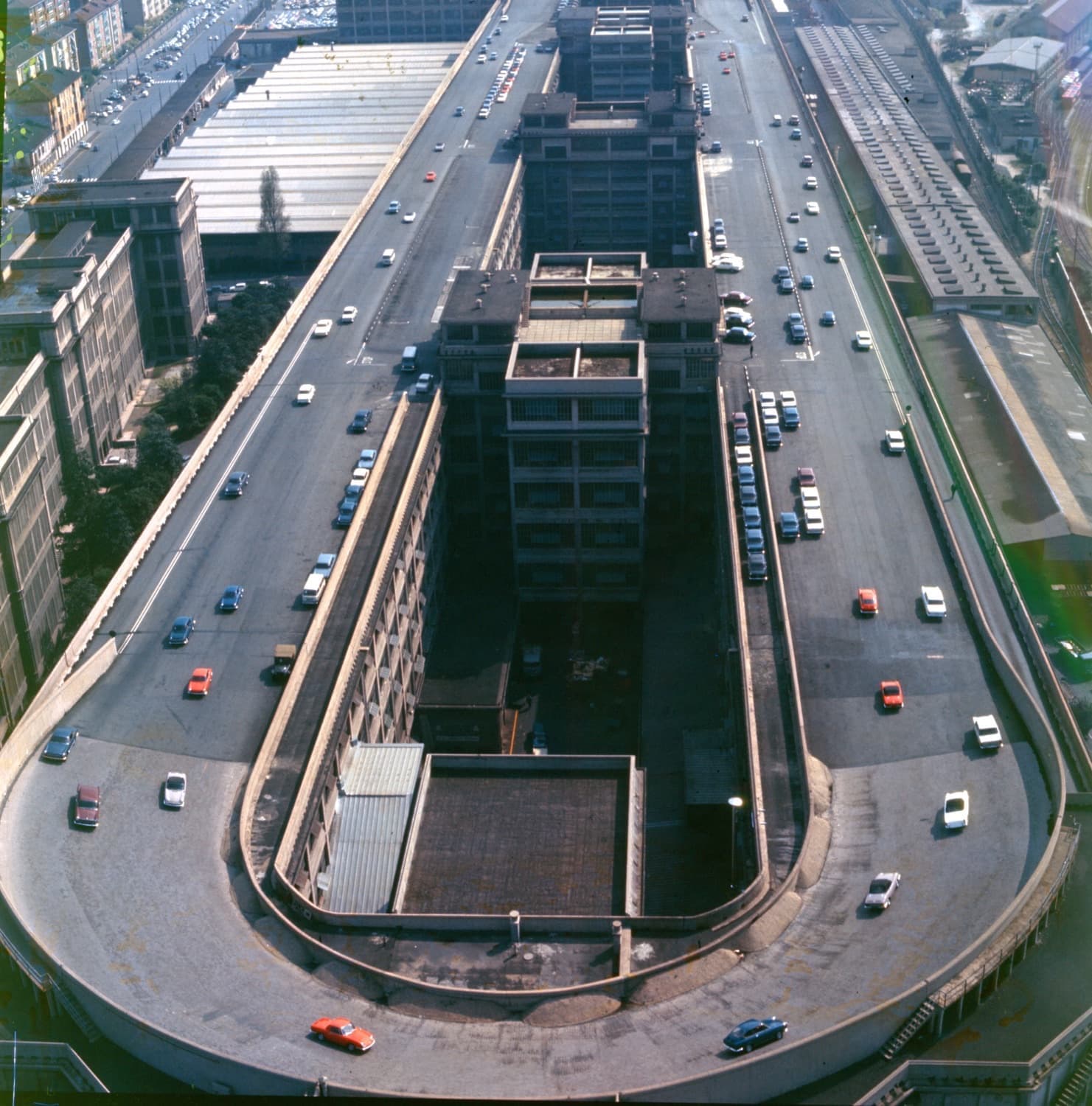 Aerial photograph of the long Lingotto factory roof with an oval test track and cars on it