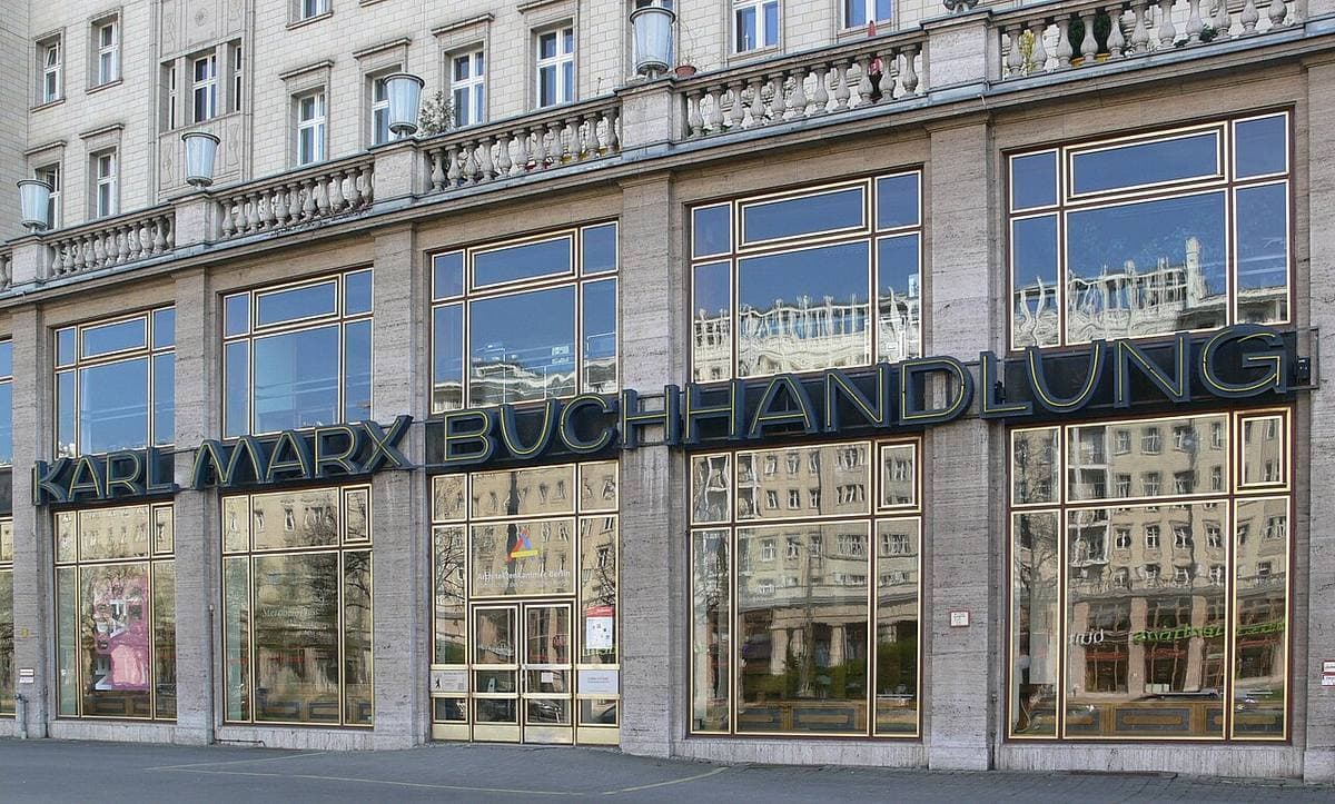 The long KARL MARX BUCHHANDLUNG sign above tall shop windows