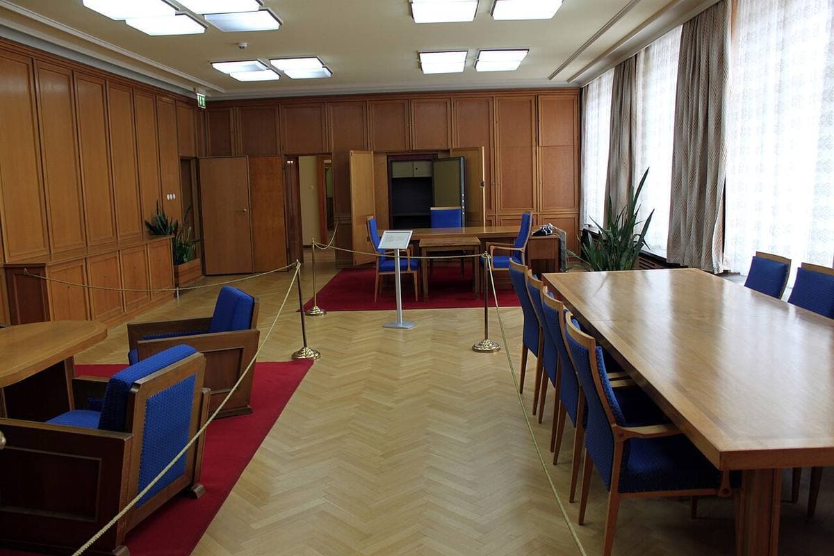 A wood-panelled office with a long conference table and blue chairs