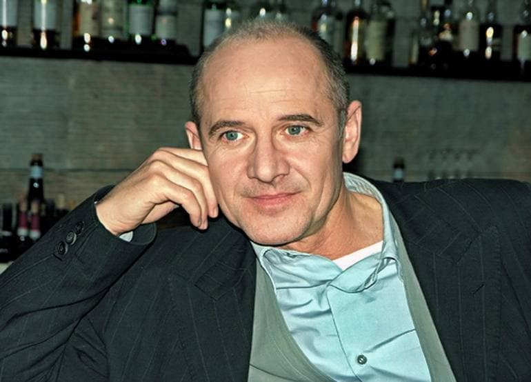 Ulrich Mühe, chin on hand, half-smiling at the camera