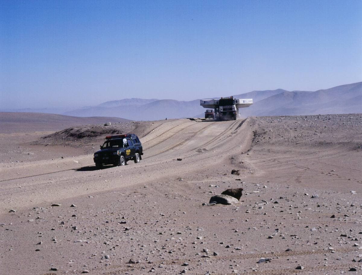 A straight road across bare desert towards distant mountains