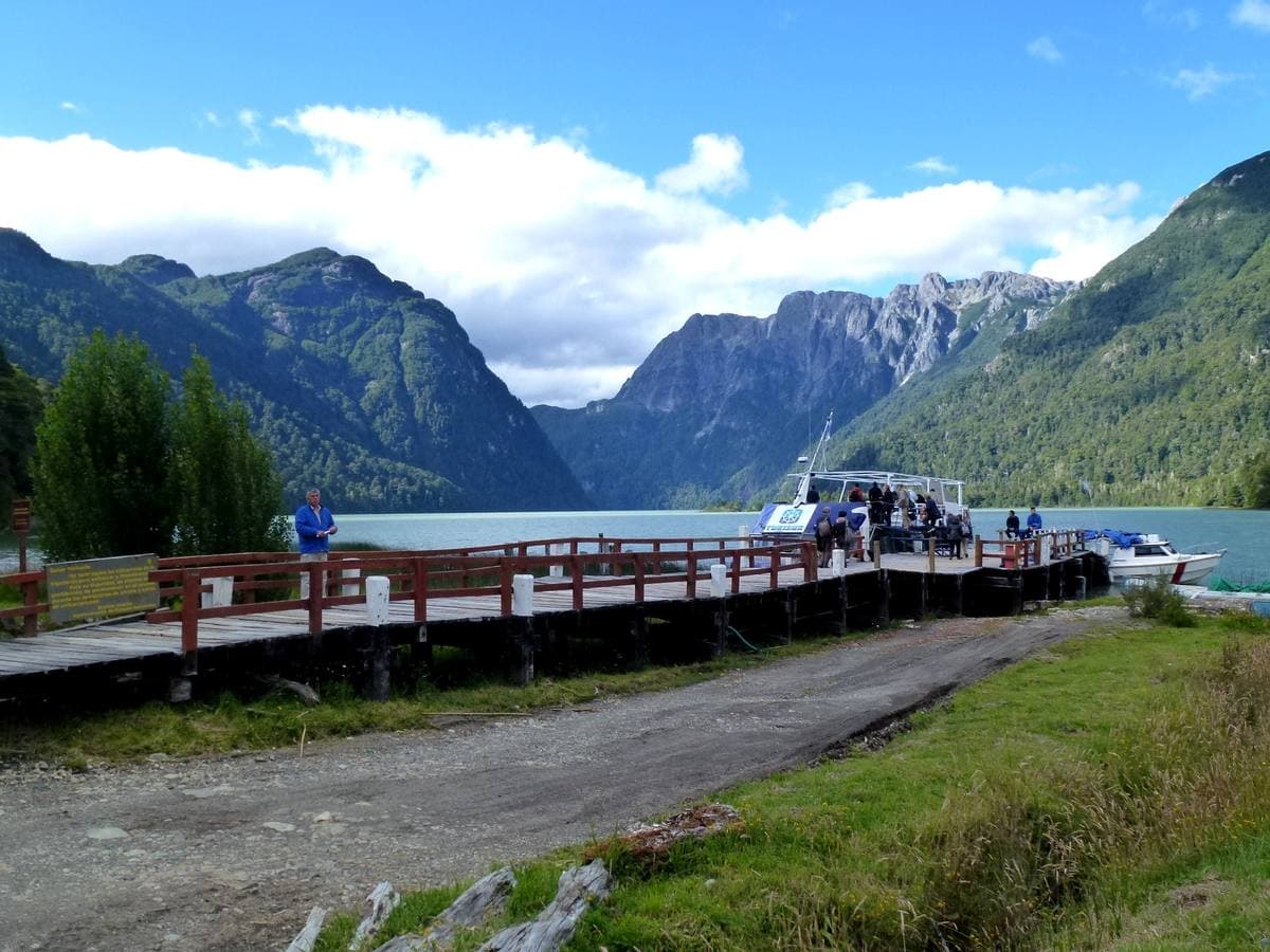 A wooden pier on a green glacial lake between steep forested mountains