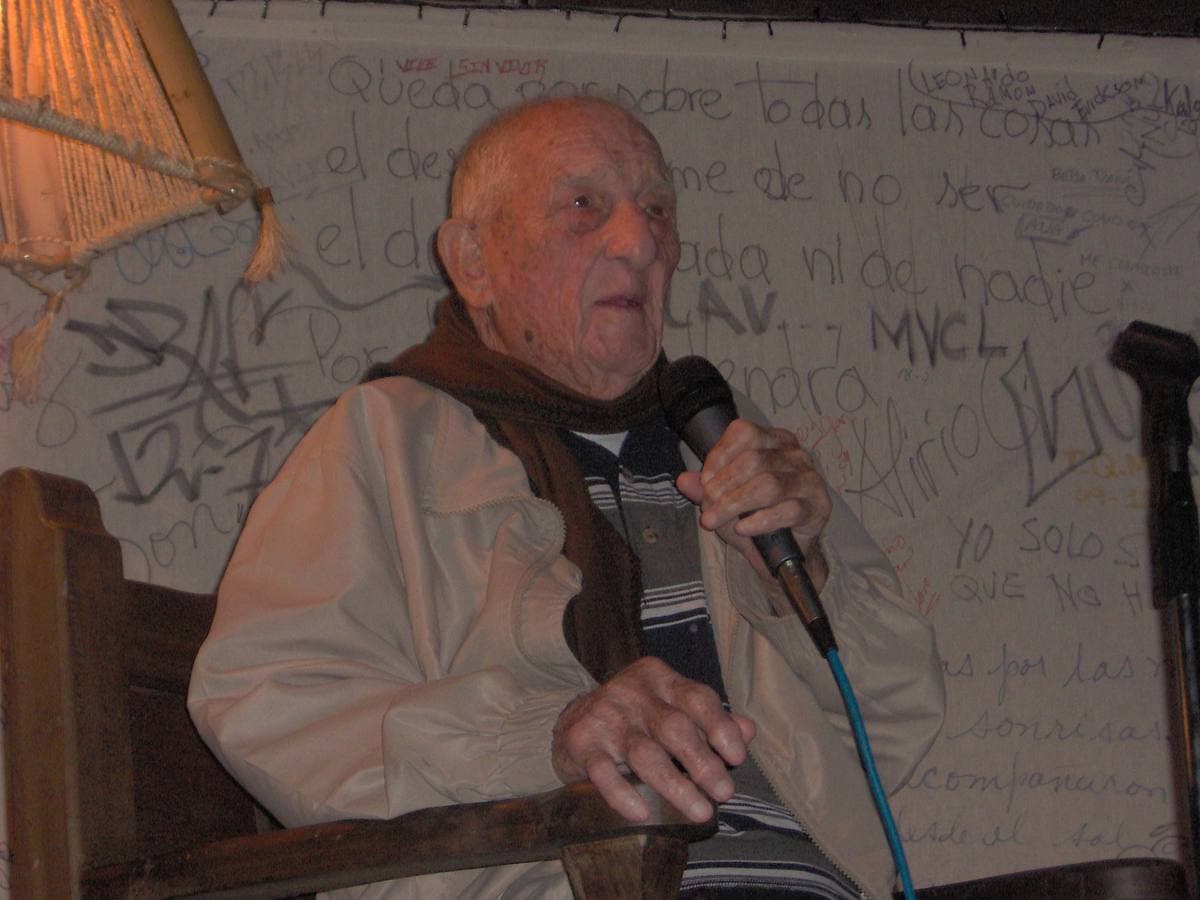 Alberto Granado, white-haired, speaking into a microphone in an armchair