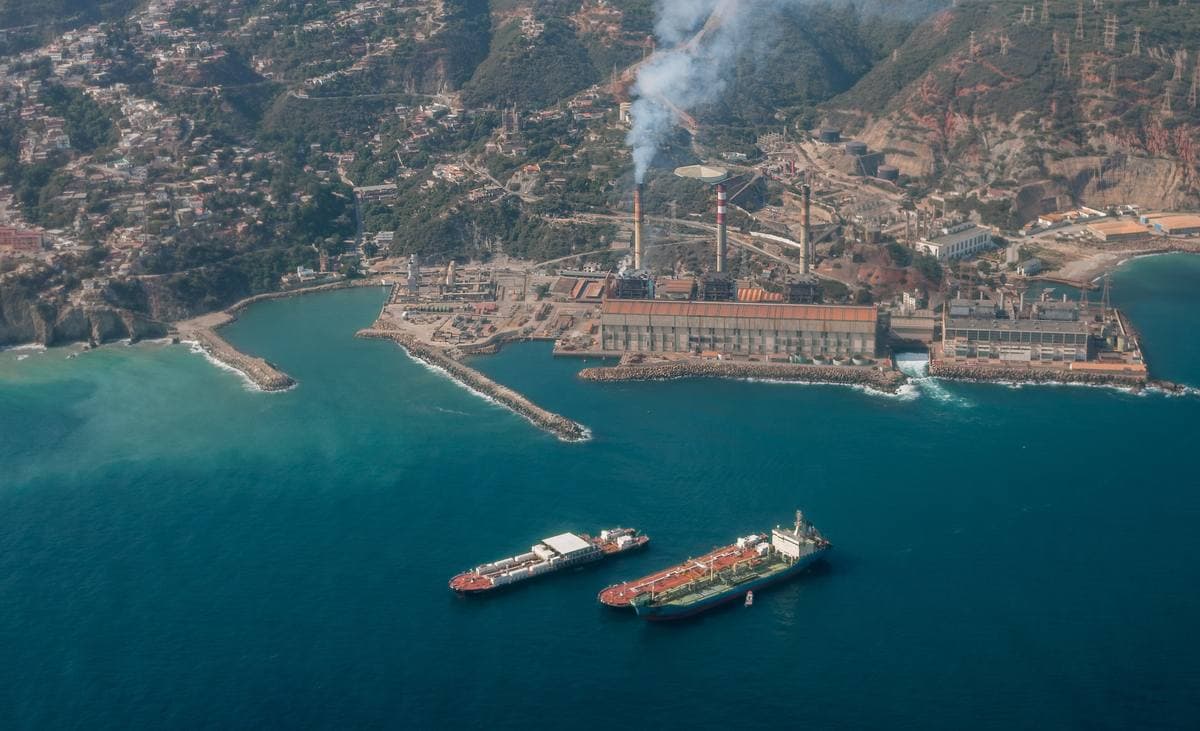 Aerial view of a harbour and coastal town between mountains and blue sea