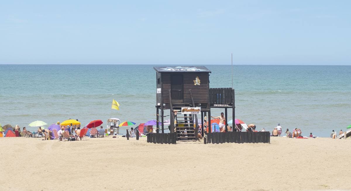 A sandy beach with umbrellas and a lifeguard hut