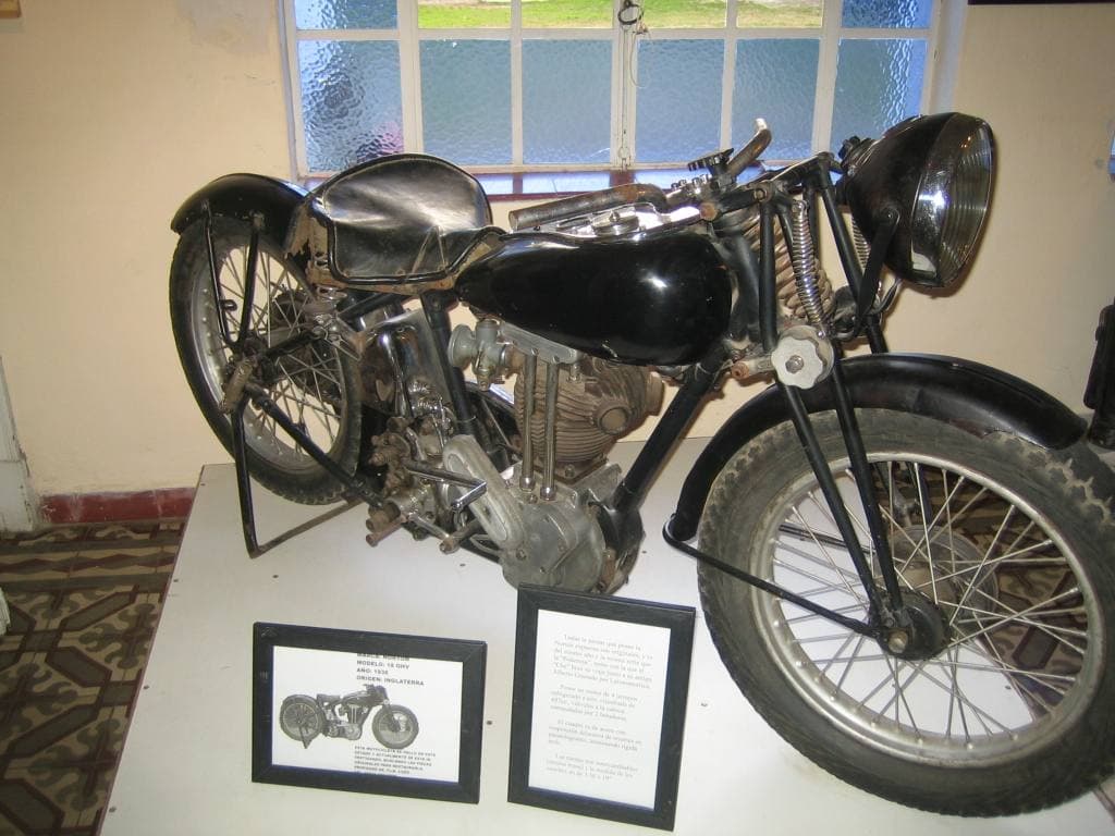 A black vintage motorcycle on display in front of a window