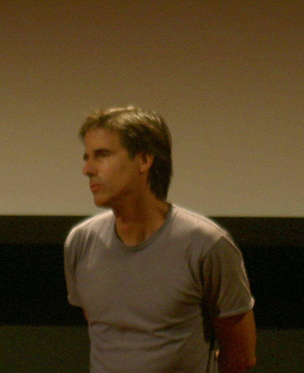 Walter Salles in a grey T-shirt standing in front of a cinema screen