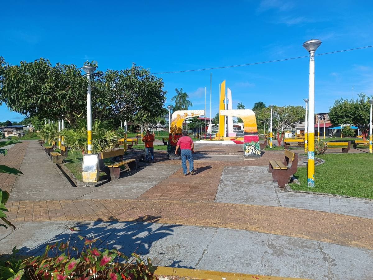 A paved plaza with lamps, palms and a yellow monument in a small Amazon town