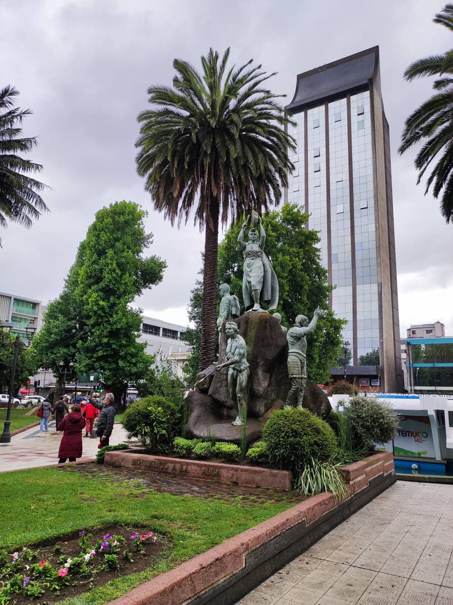 A palm tree and a bronze monument in a city square