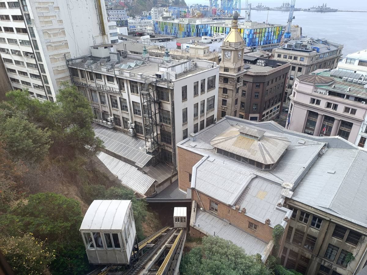 A small funicular car on a steep track above old port buildings
