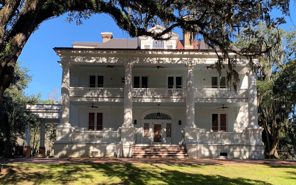 A white neoclassical house with a deep columned porch