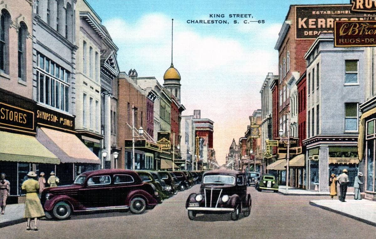 A coloured postcard of King Street with shopfronts, cars and pedestrians, about 1940
