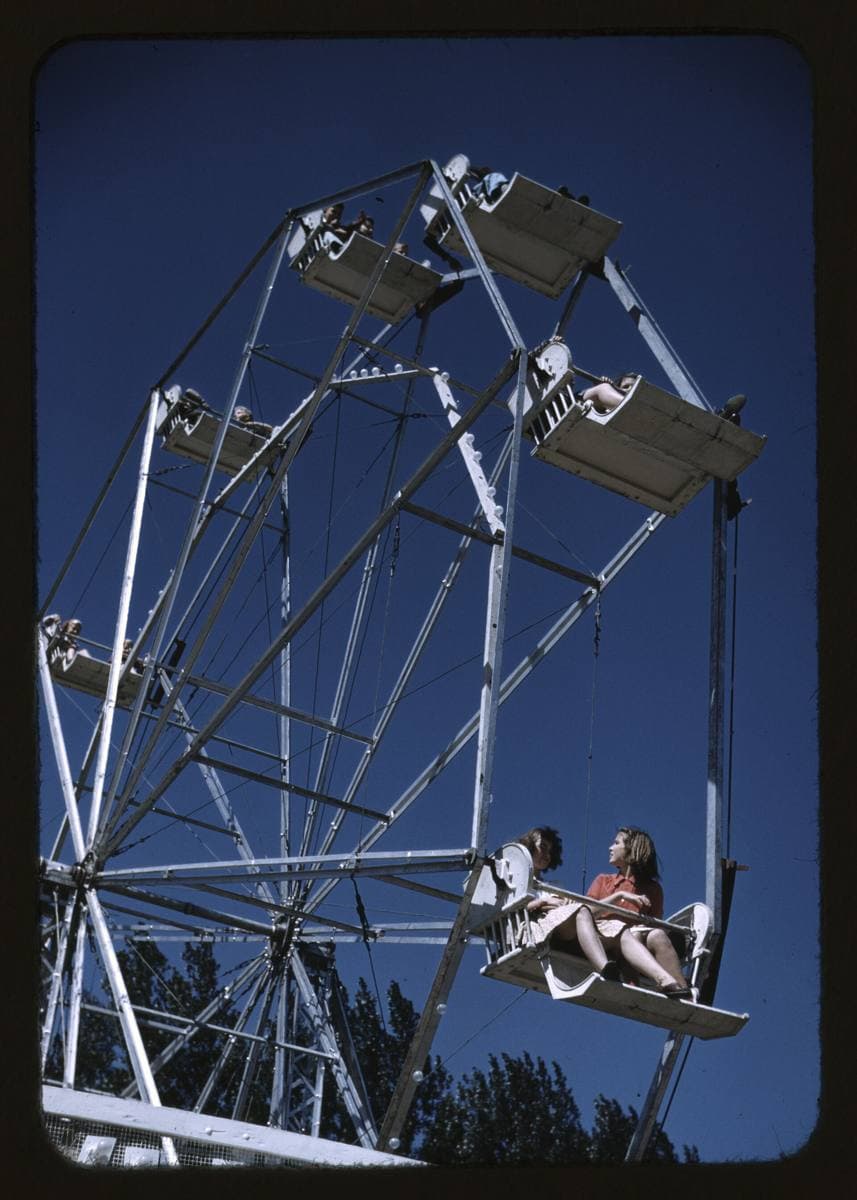Riders in the seats of a Ferris wheel against the sky, 1941