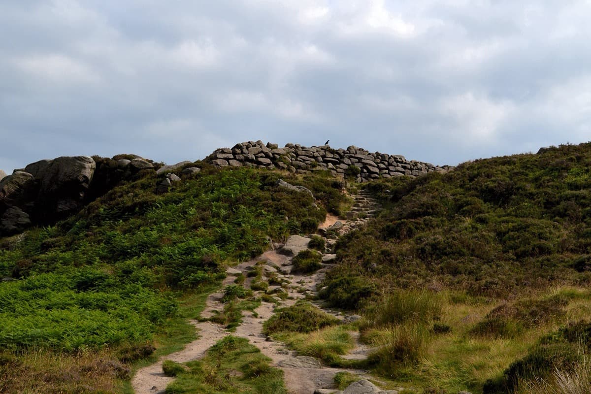 A rocky moorland promontory with a stone bank across it.
