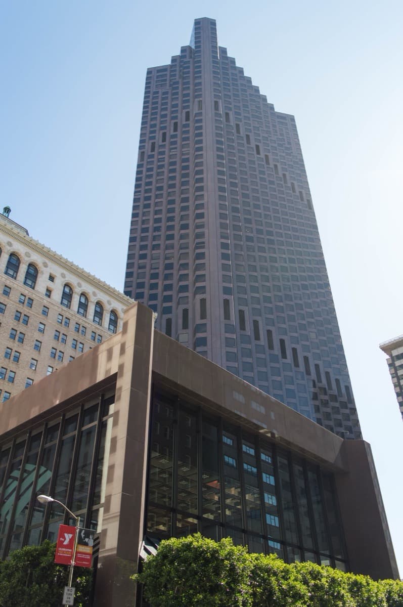 A dark faceted skyscraper rising above downtown streets