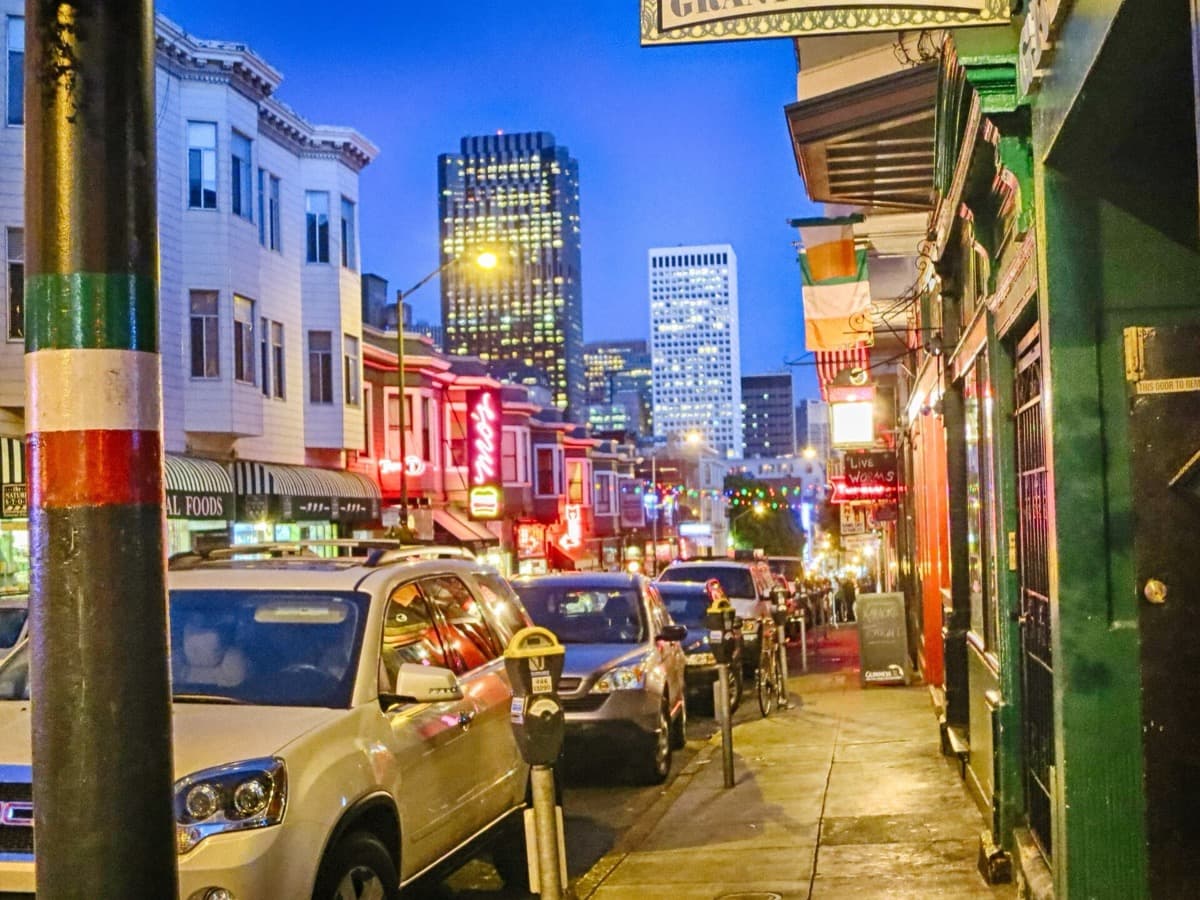 A narrow street of low shops and signs at night