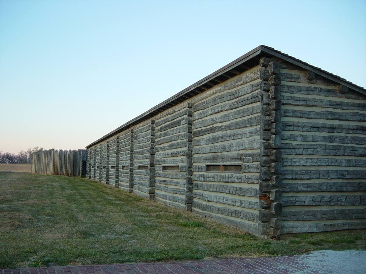 A long log rampart with small windows on a grass field
