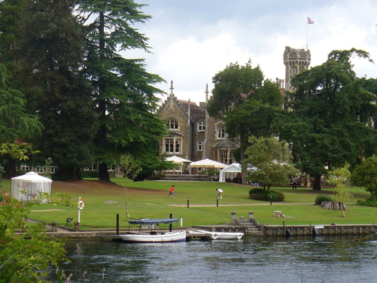 A grey Victorian Gothic house with pointed gables seen across a lawn